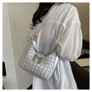 Close-up of silver woven shoulder bag featuring a metallic bow and knotted strap detail