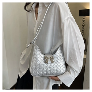 Close-up of silver woven crescent bag with metallic finish and bow detail on a model