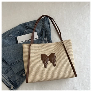 Macro detail of hand-woven straw tote bag with leather bow and retro denim texture