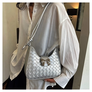 Detail shot of silver woven texture shoulder bag with metallic bow clasp and knotted strap