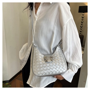 Close-up of a metallic silver woven shoulder bag featuring a decorative metal bow clasp