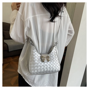 Detail of silver woven crescent bag featuring a stylish metallic bow clasp on the flap