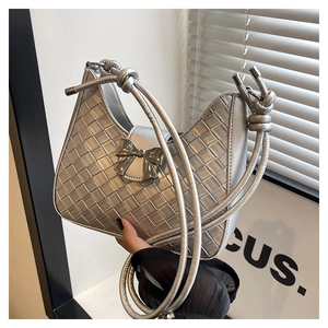 Close-up of a silver woven underarm bag with a metallic bow and knotted strap detail