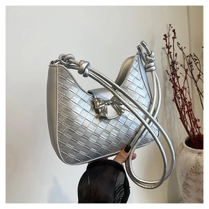 Macro shot of silver woven shoulder bag with a metallic bow buckle and curved handle