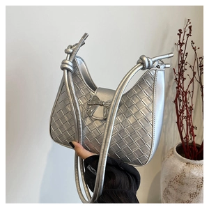 Close-up of a silver woven crescent moon bag featuring a chic metal bow and knotted handles