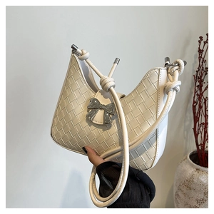 Detail of white woven underarm bag with silver bow accent and knotted shoulder strap