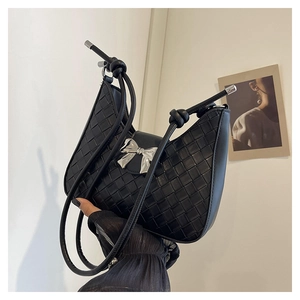 Detail of black woven crescent bag featuring a metallic silver bow and knot handle