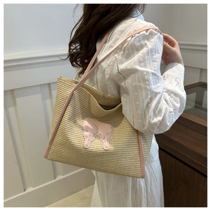 Detail of handwoven straw tote bag with 3D pink butterfly applique and leather straps