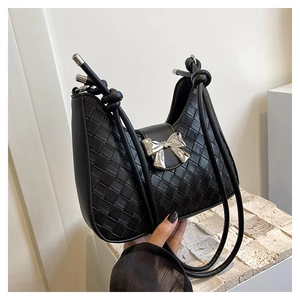 Macro view of black woven texture leather bag featuring a silver metal bow detail