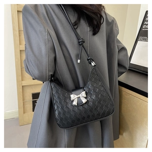 Detailed view of black woven shoulder bag with silver bow accent and adjustable strap