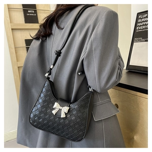 Detail of woven black hobo bag with metallic silver bow worn on a grey suit jacket
