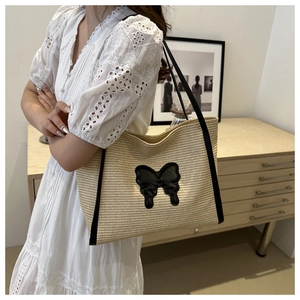 Close-up of woven tote bag featuring a black butterfly applique and matching long straps