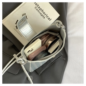 Interior view of light grey quilted bag showing capacity for phone and cosmetics