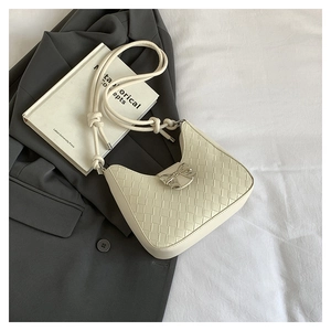 Detail of cream woven shoulder bag featuring a silver metal bow buckle on a suit jacket