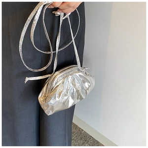 Close-up of a mini silver metallic pleated cloud bag held by a model for a chic look