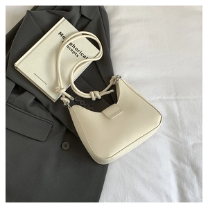 Detail of a creamy white leather hobo bag with a unique knotted shoulder strap design
