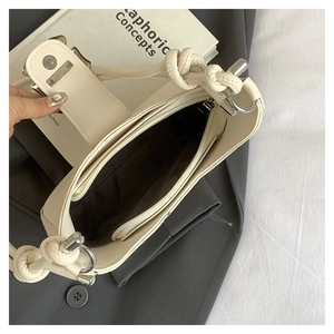 Close-up of cream woven crescent bag interior with zipper pocket and magnetic closure