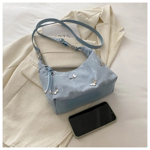 Gros plan du sac à bandoulière bleu clair à motif marbré et breloques papillon argent