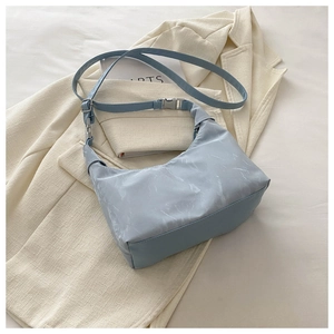 Détail du sac à main bleu clair motif marbre avec boucle en argent sur tissu blanc