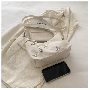 Détail du sac demi-lune beige avec papillons argentés et tirette de fermeture nouée