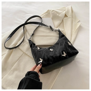 Détail du sac demi-lune plissé noir avec ornements papillon en argent et bandoulière en cuir