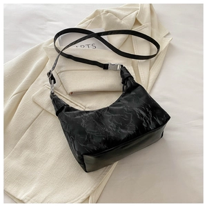 Gros plan du sac bandoulière en cuir plissé noir avec boucles argentées sur un blazer