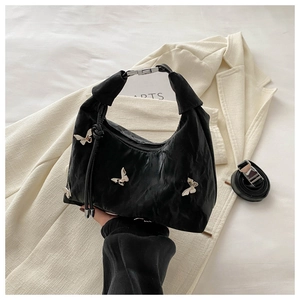 Détail d'un sac à main noir plissé avec breloques papillons argentés et fini brillant
