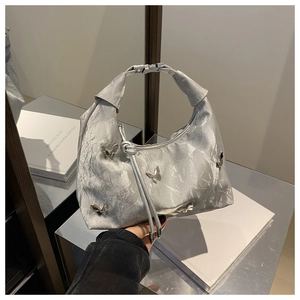 Détail du sac à main argenté avec appliques papillon 3D et poignée à nœud design