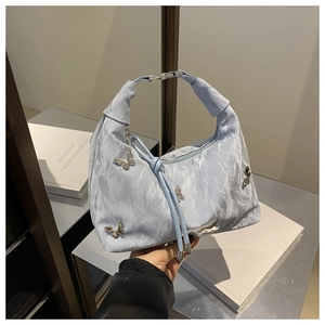 Gros plan du sac plissé bleu clair avec breloques papillon argentées et cordon décoratif