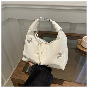 Detail view of the white pleated handbag featuring decorative silver butterfly metal charms