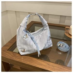 Détail du sac hobo plissé bleu clair avec un ornement métallique en papillon argenté