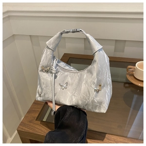 Detailed shot of silver textured handbag featuring three 3D metallic butterfly accents