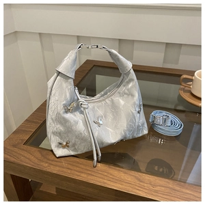 Détail du sac hobo argenté avec papillons en métal et poignée à nœud élégante