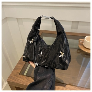 Detail of black pleated hobo bag with 3D white butterfly accents and metallic buckle handle