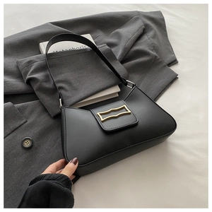 Gros plan du sac croissant noir avec boucle en métal doré vintage sur un blazer gris