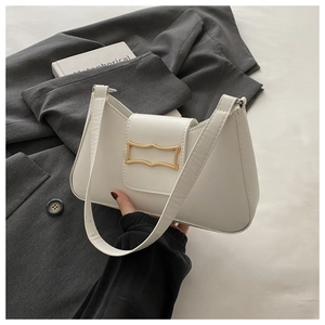 Détail du sac croissant en cuir blanc arborant une boucle dorée ondulée distinctive
