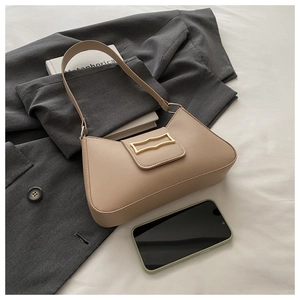 Détail d'un sac demi-lune beige minimaliste avec boucle dorée sur un tissu blanc