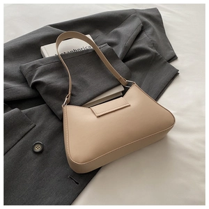 Sac croissant crème chic posé sur un blazer gris pour un look minimaliste élégant