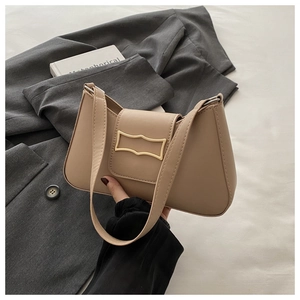 Sac baguette beige chic avec boucle dorée sur fond de blazer neutre et livre élégant