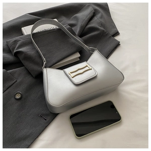 Détail d'un sac porté épaule argenté avec boucle dorée sur un blazer de bureau chic