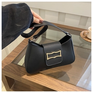 Détail du sac croissant noir avec boucle en métal doré élégante sur une table en bois