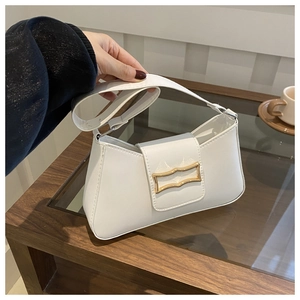 Détail du sac croissant blanc avec boucle en métal doré et texture de cuir synthétique