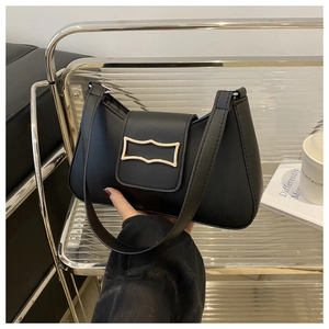 Vue détaillée du sac demi-lune en cuir noir avec boucle dorée tenu à la main