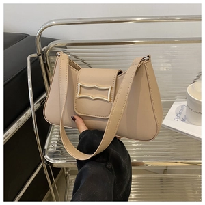 Détail du sac croissant beige minimaliste avec un fermoir à boucle métallique dorée