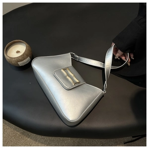 Détail du sac en cuir argenté avec une boucle dorée distinctive en forme de vague
