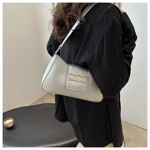 Détail du sac à bandoulière croissant argenté avec boucle dorée porté à l'épaule