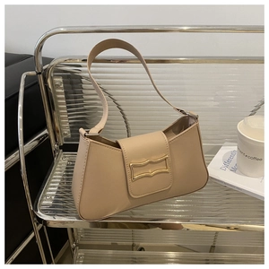 Détail d'un sac demi-lune en cuir beige avec boucle dorée sur un support métallique