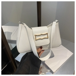 Détail du sac sous l'aisselle blanc avec boucle dorée ondulée et large bandoulière