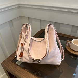 Pink vintage hobo bag with metal bow and amber bead charm on a wooden table