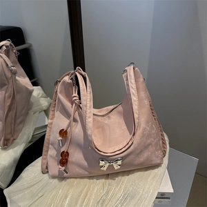 Pink velvet shoulder bag with silver bow accent and bead charm on white fabric